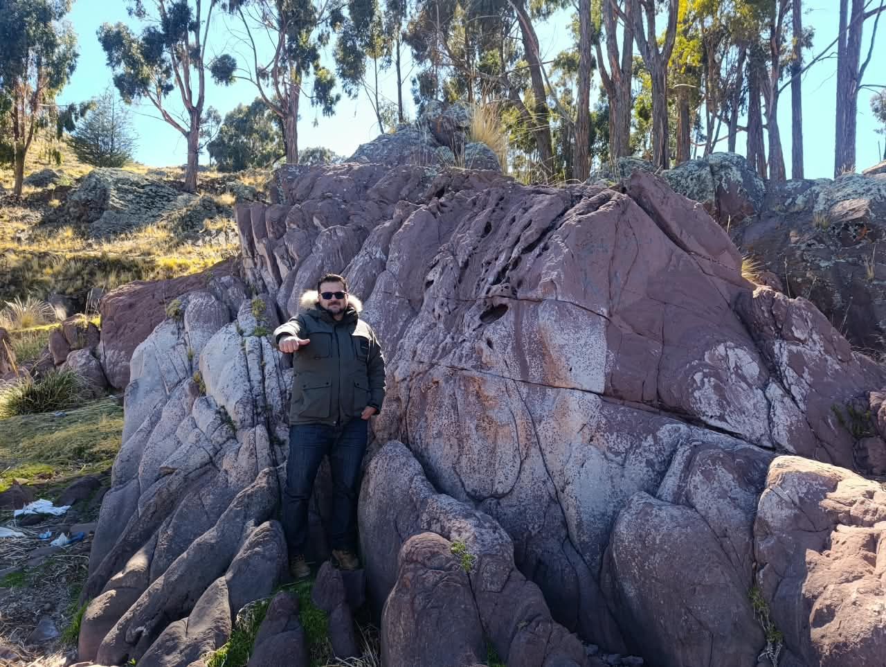 Viajero sentado sobre rocas rojizas bajo un cielo azul
